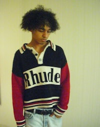 a young man wearing a sweater with the word rhude on it