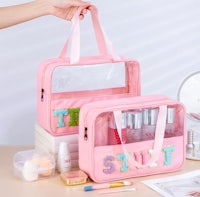 a pink cosmetic bag with cosmetics on top of it