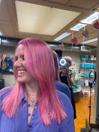 a woman with pink hair in front of a mirror