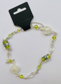 a bracelet with green glass beads and a black tag