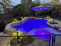 a swimming pool with a blue umbrella and lights