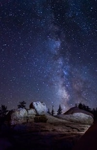 the milky in the night sky above a rock formation