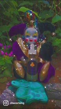 a stuffed jester sitting in a garden