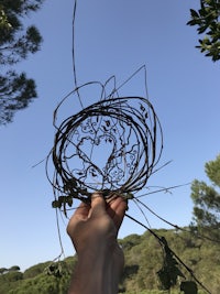a person holding up a piece of twigs with a heart in the middle