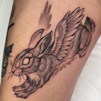 a black and grey tattoo of a rabbit with wings