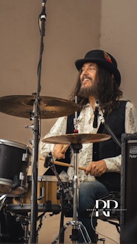 a man wearing a hat and playing drums