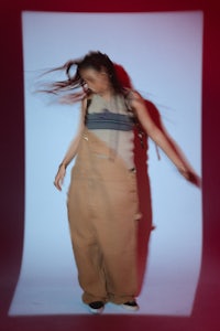 a woman in overalls with her hair blowing in the wind