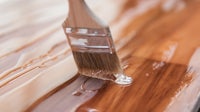 a person is painting a wooden surface with a brush
