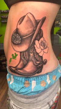 a tattoo of a cowboy hat and boots on a woman's stomach