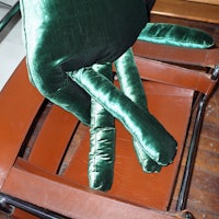a green stuffed animal sitting on a chair