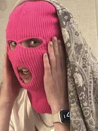 a person wearing a pink knitted face mask