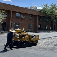a man is laying asphalt on a street in front of a building