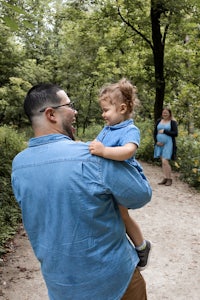 a man holding a child in the woods