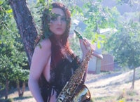 a woman with a saxophone in front of a tree
