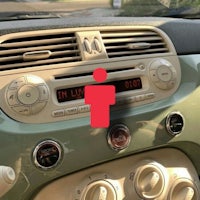 the dashboard of a car with a red button on it