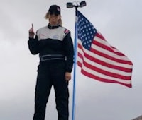 a woman standing on top of a hill with an american flag