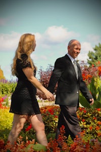 a man and a woman walking through a flower garden