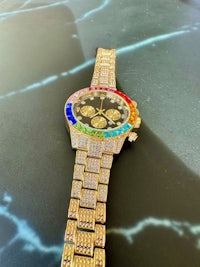 a gold watch with multi colored stones on it