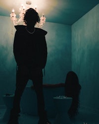 a man standing in front of a bathtub with a chandelier
