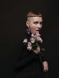a woman with a shaved head holding a bouquet of roses
