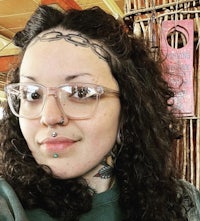 a woman with glasses and piercings is posing for a photo