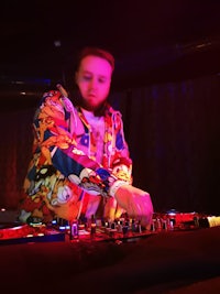 a man in a colorful jacket is djing at a nightclub