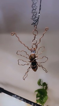 a copper beetle hanging from a chain