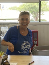 a woman in a blue shirt smiling at a table