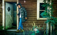 a man in a plaid coat standing in the doorway of a house