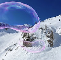 two soap bubbles floating in the air over a snow covered mountain
