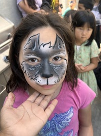 a little girl with a face painted like a wolf