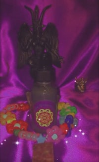 a bottle of purple liquid with a demon on it