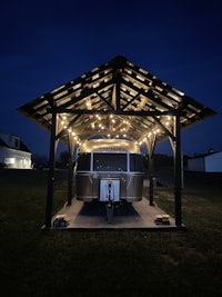 a wooden gazebo with lights on it at night