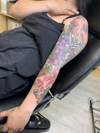 a woman sitting in a chair with a flower tattoo on her sleeve