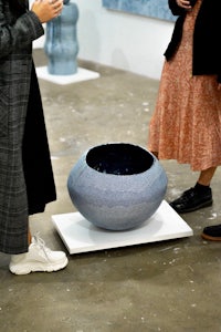 a group of people standing in front of a blue vase