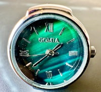 a green watch with the word gomia on it