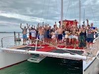 a group of people standing on the top of a catamaran