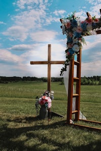 a wedding arch with a cross in the middle of a field