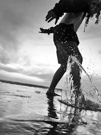 black and white photo of a boy playing in the water