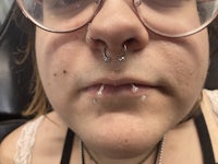 a woman wearing glasses with a nose piercing