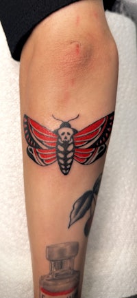 a tattoo of a moth on a person's leg