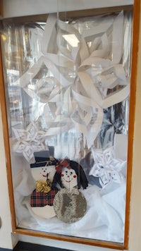 a window display with paper snowmen and snowflakes