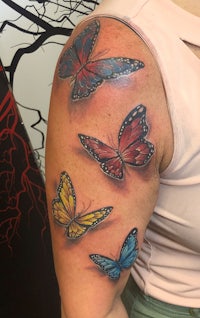 a woman with a colorful butterfly tattoo on her arm