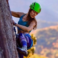 a woman wearing a helmet climbing a rock