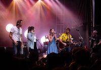 a group of people singing on stage at a concert