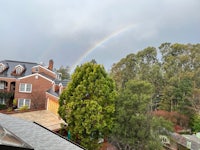 a rainbow is seen from the roof of a house