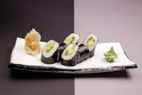 sushi on a white plate with a black background