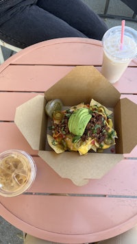 a plate of nachos with guacamole and a drink on a table