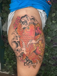 a woman with a koi fish tattoo on her thigh