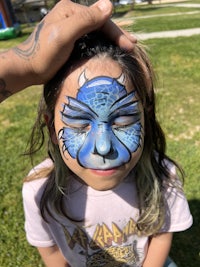 a girl with a blue face painted on her head
